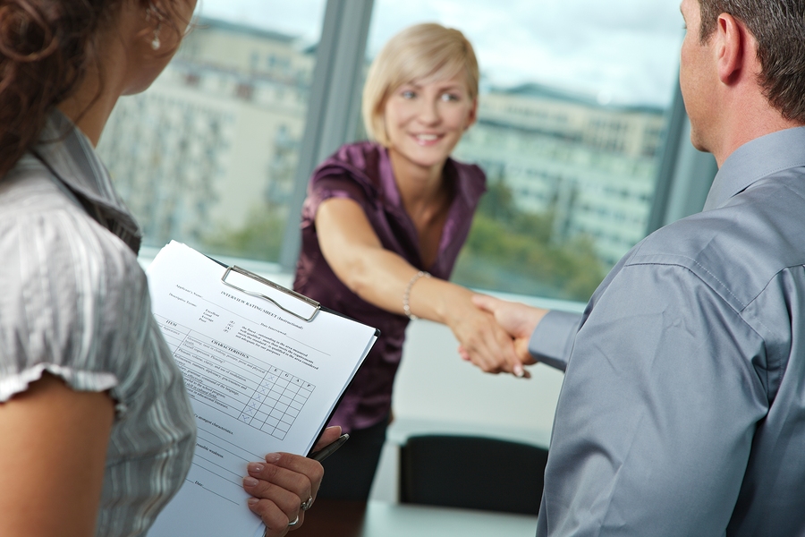 Successful job interview - happy employee shaking hands, smiling. Focus places on questionnarie in front, reults are excellent.